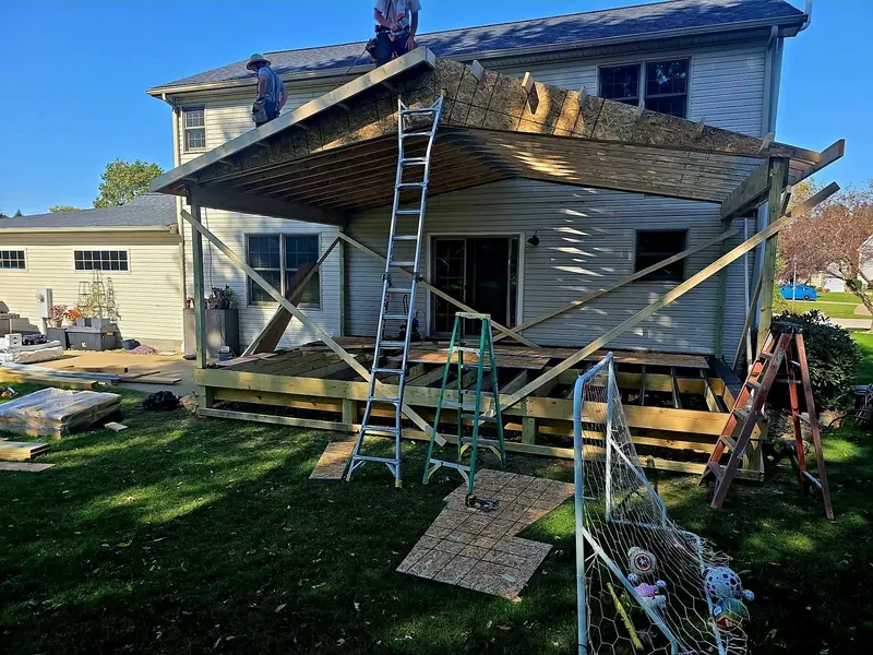 Crew framing a covered porch and deck behind a two-story home