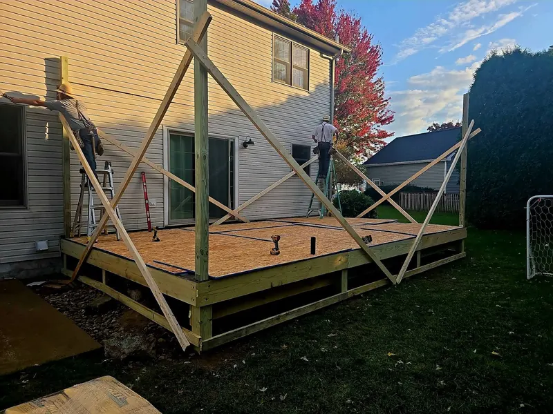 New deck frame and decking platform with bracing behind a two-story house