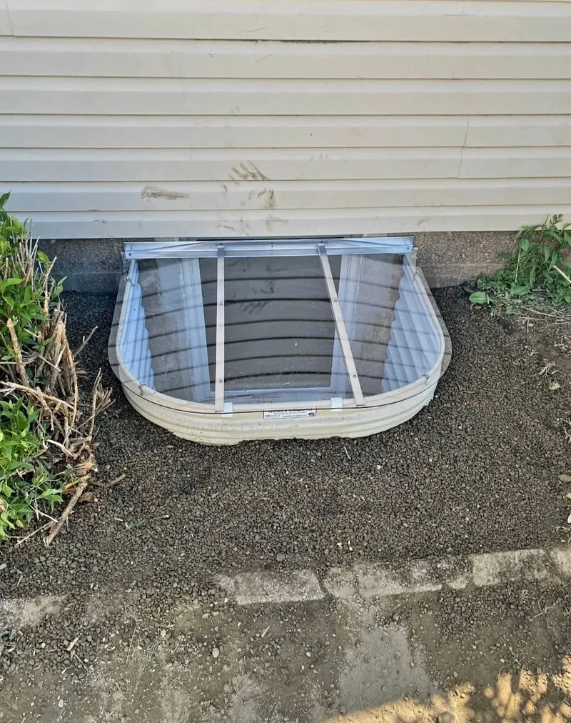 New egress window well installed against a sided foundation wall