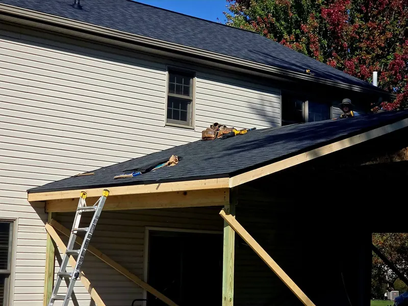 Fresh dark shingles on a new porch roof attached to a sided home