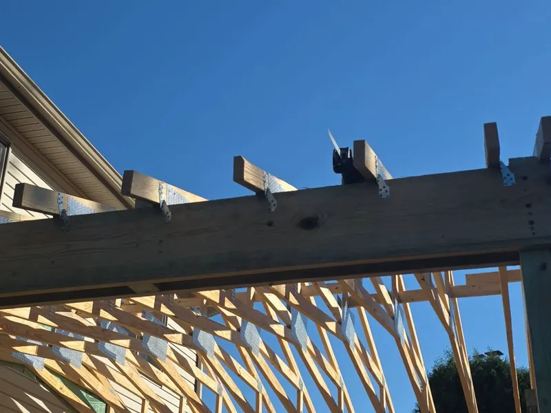 Close-up of structural framing and metal connectors under a clear blue sky